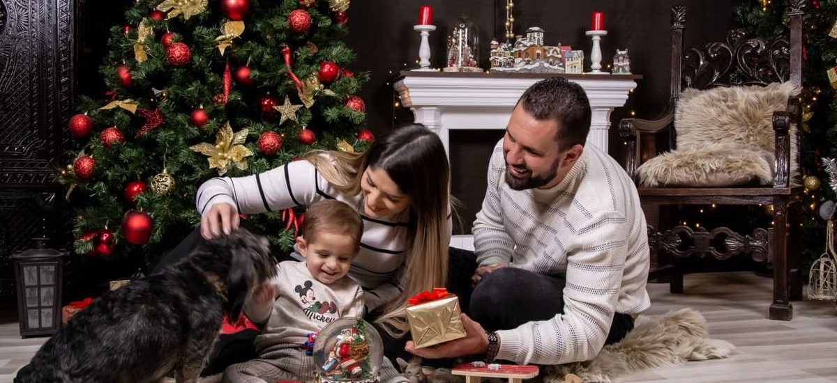 A joyful moment with family by the Christmas tree, gifting and playing with a dog.