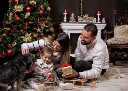 A joyful moment with family by the Christmas tree, gifting and playing with a dog.